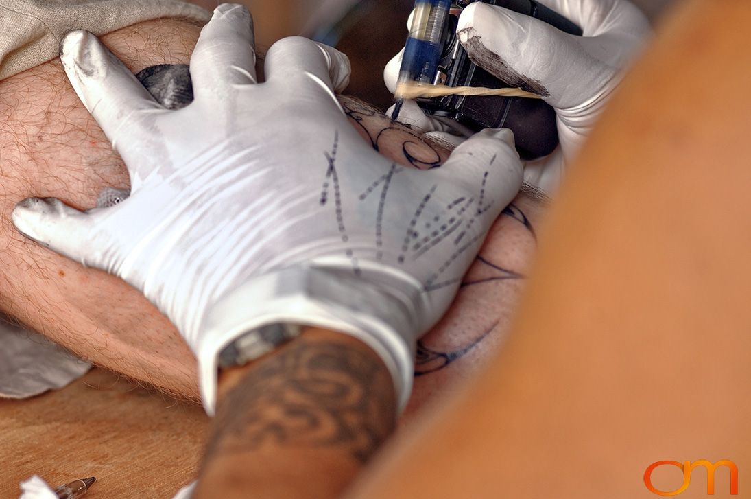 Photo of Polynesian tattoo artist applying a traditional tattoo design on a tourist's leg. Taken of Santos on the Marquesas island of Hiva Oa by Amanda Fornal in October 2006.